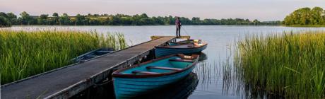 Man fishing from a wooden dock on a lake surrounded by small boats