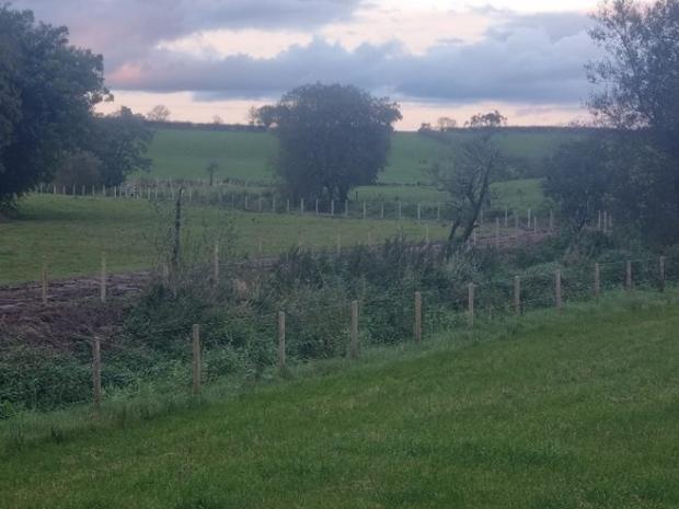 Fencing along both sides of a river running through fields